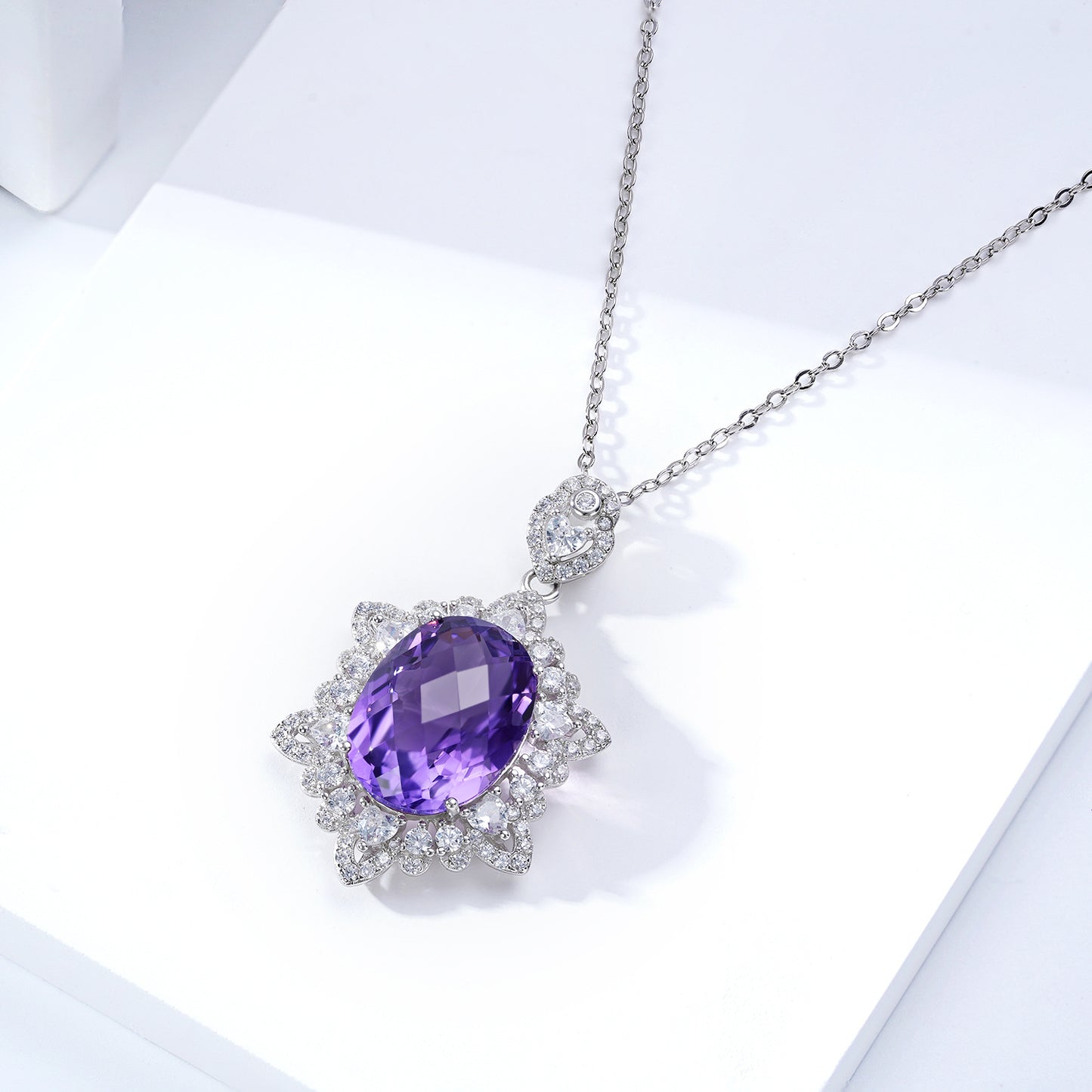 Silver necklace with a purple gemstone on a white background