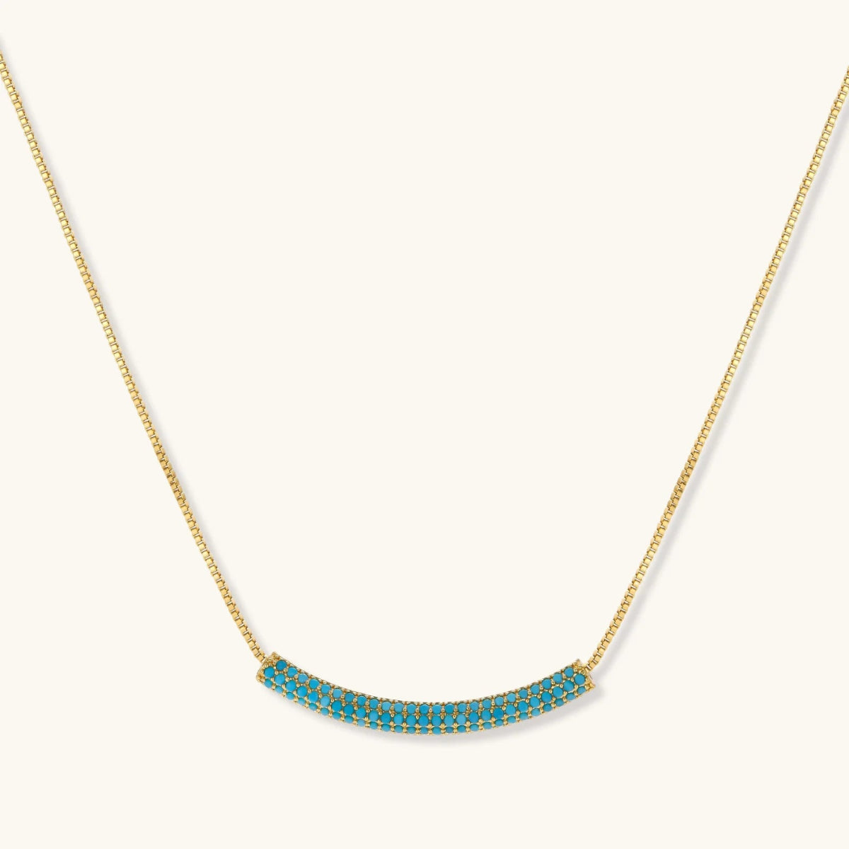 Gold-plated curved necklace and hoop earrings with turquoise cubic zirconia stones.