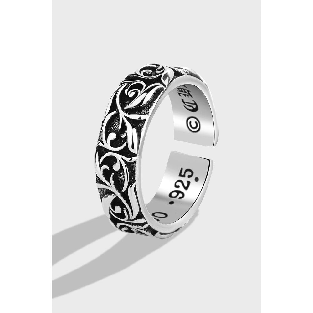 Silver ring with intricate designs on a white background