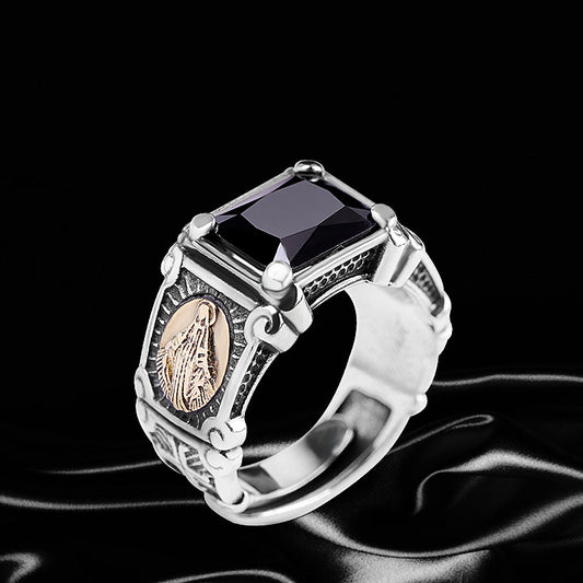 Silver ring with black gemstone and gold emblem on a black background