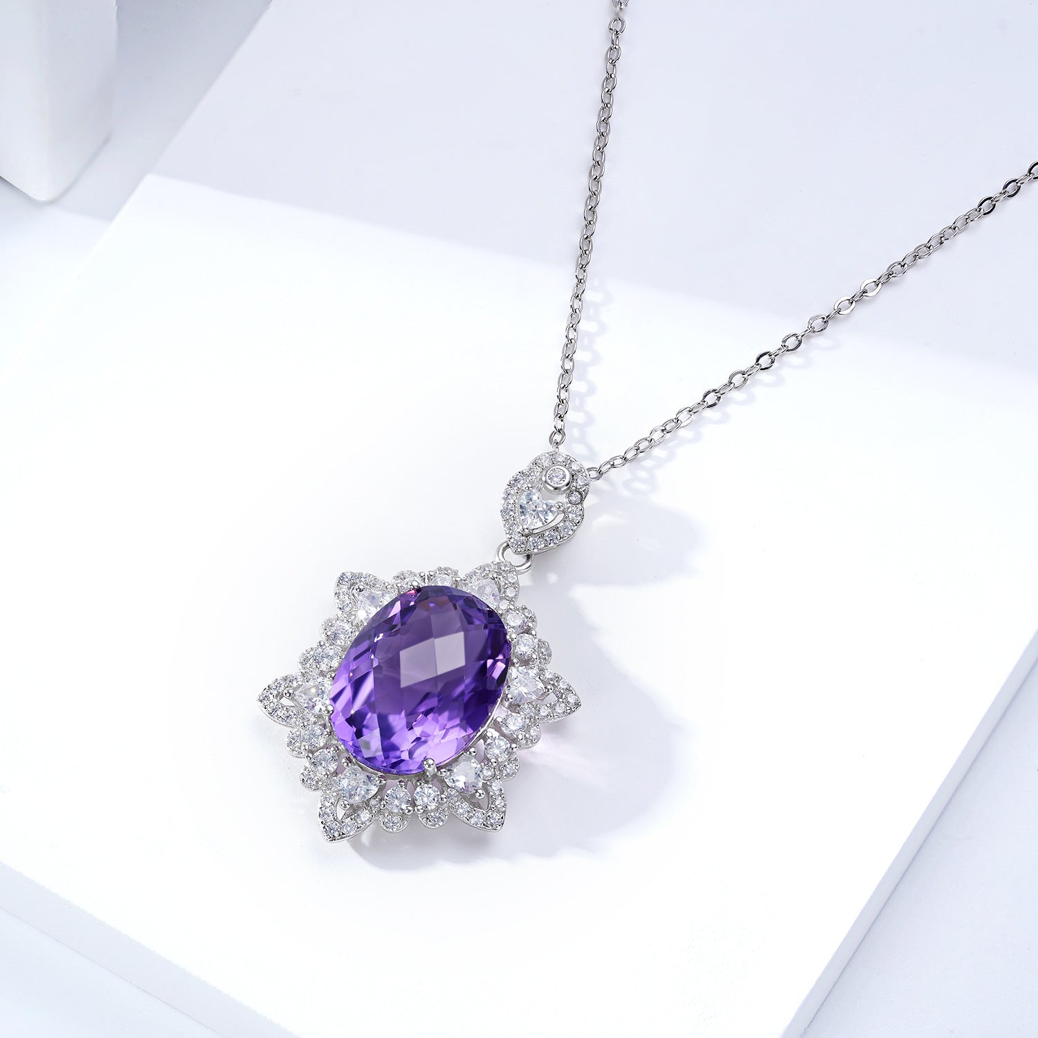 Silver necklace with a purple gemstone on a white background