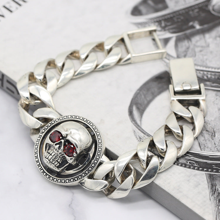 Silver chain bracelet with skull design on a marble surface